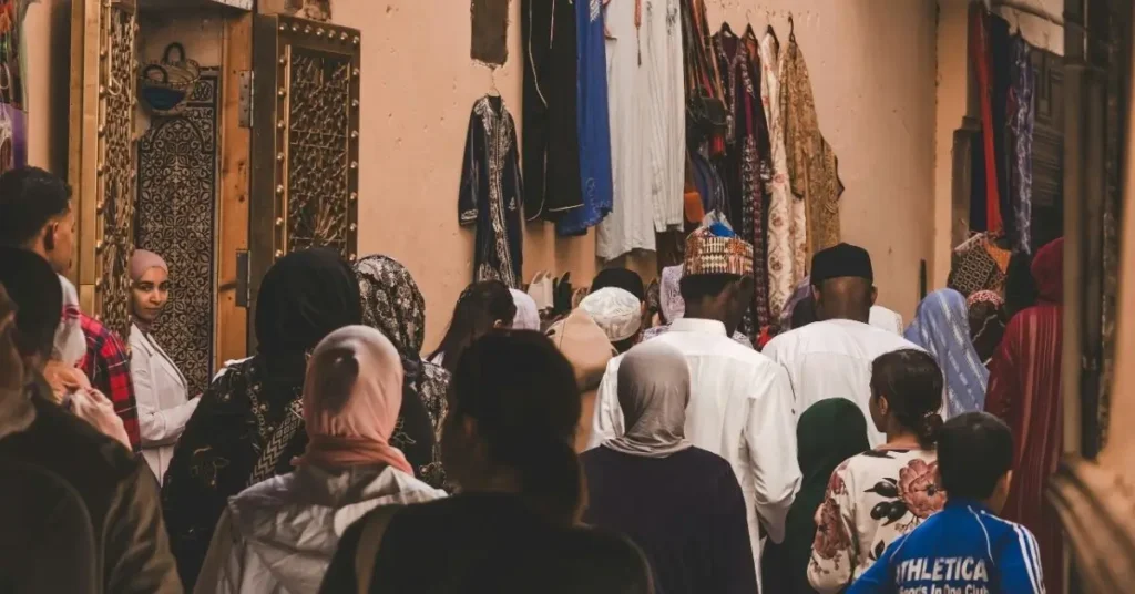 Calle concurrida en la medina de Marruecos con gente local y vestimenta tradicional.