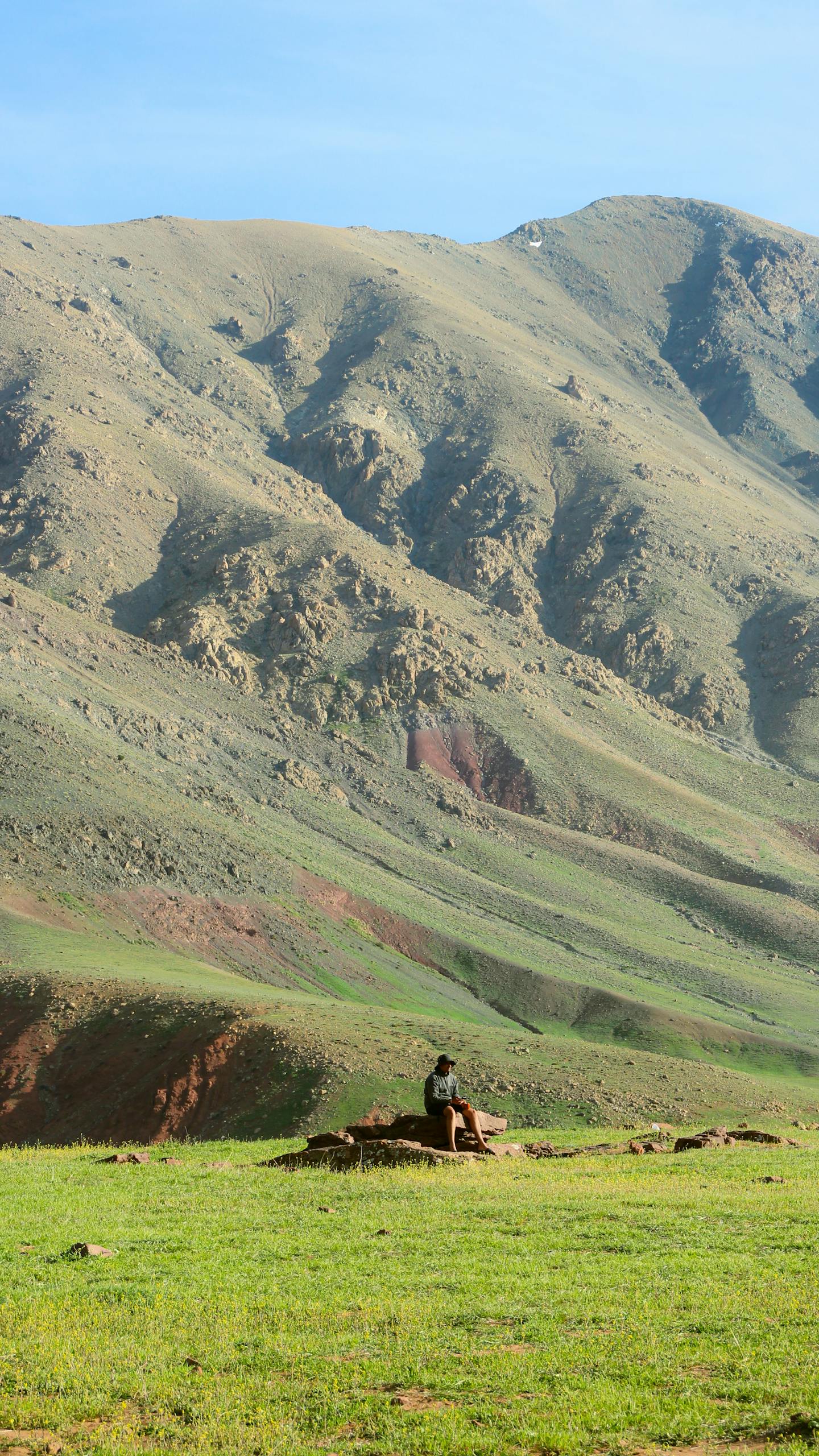 A lone traveler sits amidst the stunning mountains near Marrakesh, Morocco, showcasing nature's grandeur.