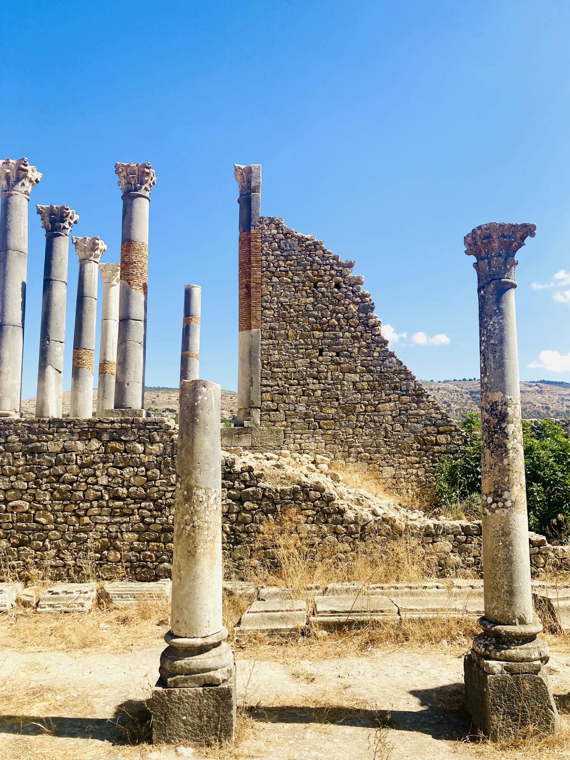 Explore ancient Roman ruins under a clear blue sky in El Menzeh, Morocco.