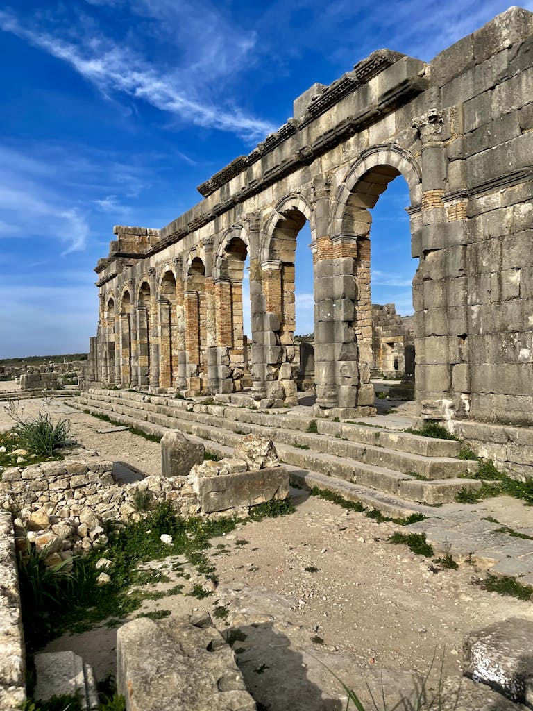 Explore the intricate remains of ancient Roman ruins basking in sunlight under a vivid blue sky.