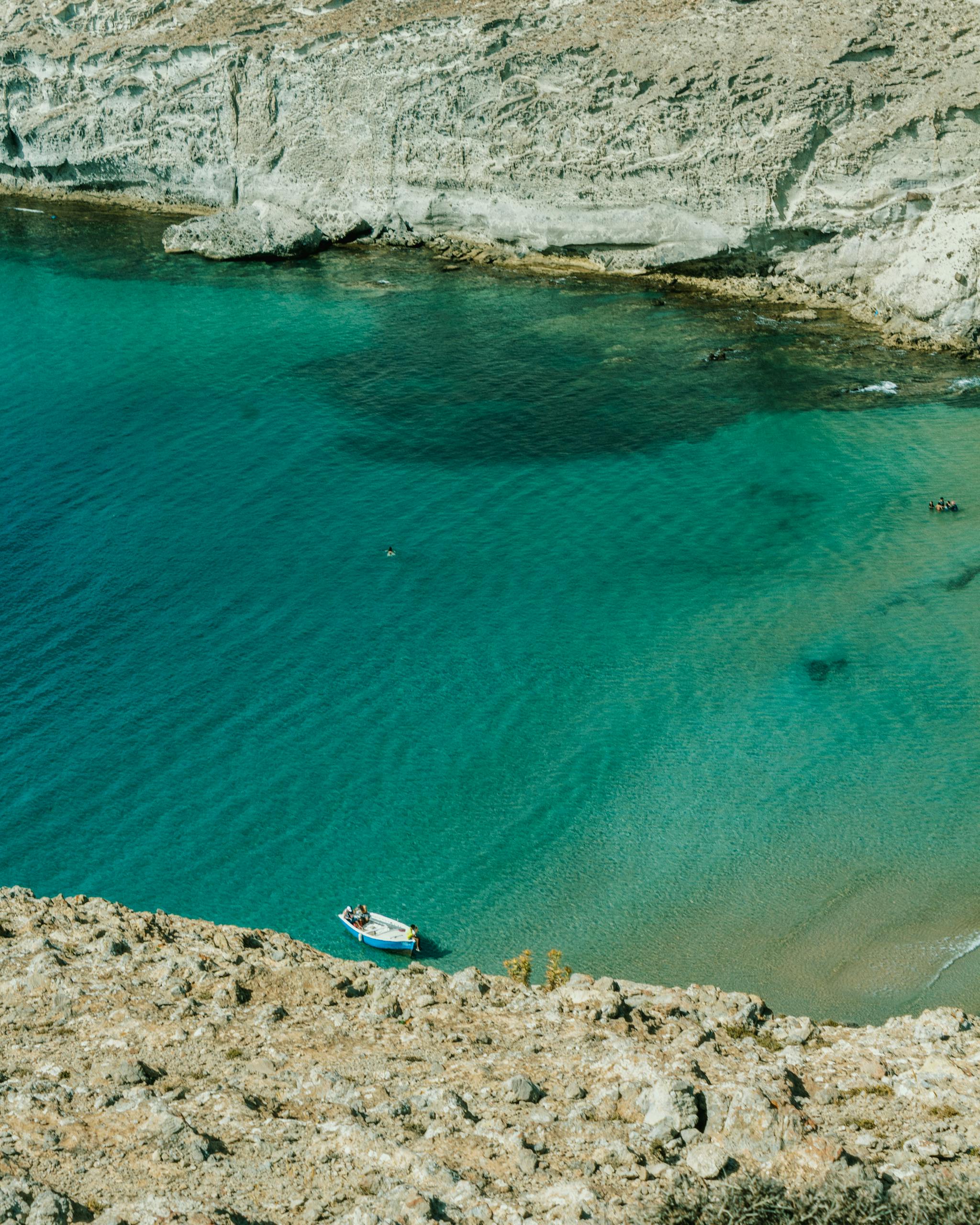 Scenic aerial view of a peaceful turquoise beach and rocky cliffs in Nador, Morocco, under clear skies.