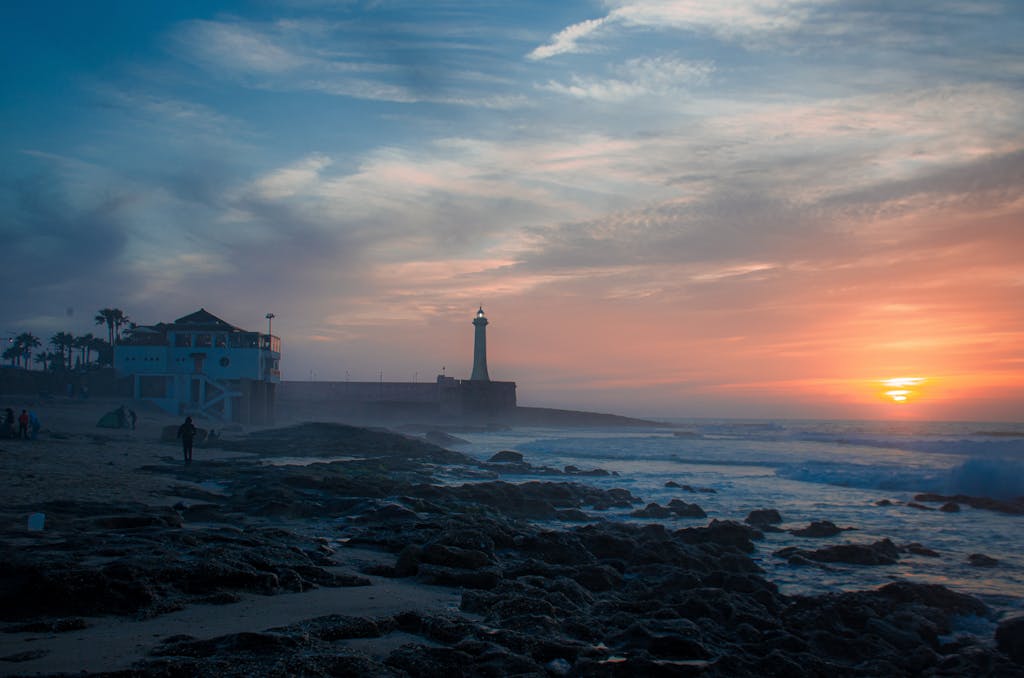 Vibrant sunset at Rabat beach highlighting the serene lighthouse.